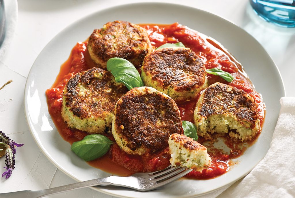 White bean, cauli and zucchini patties with spicy tomato and basil sauce lentil patties on a red plate