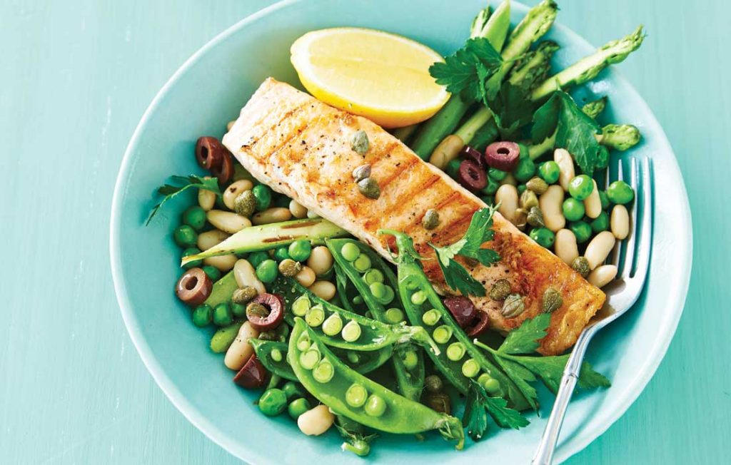 Grilled salmon and peas, beans and asparagus on a light blue plate