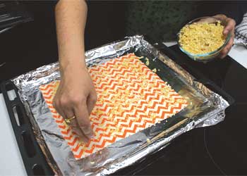 Sprinkiling beeswax on fabric on roasting tray Sprinkiling beeswax on fabric on roasting tray