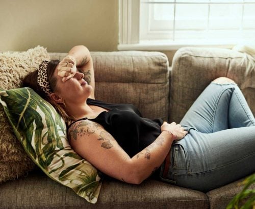 Woman lying on sofa with sore stomach