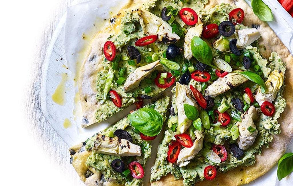 Vegan pizza with an olive crust and avocado and butter bean topping Vegan pizza with an olive crust and avocado and butter bean topping