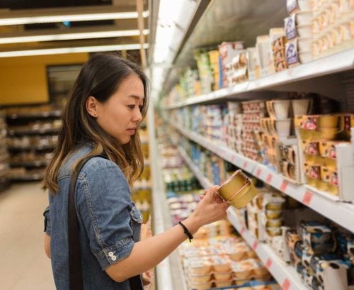 Woman reading yoghurt label in supermarket