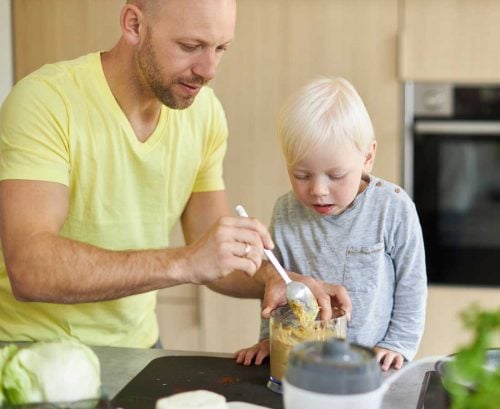 Father and young son making homemade dip/hummus