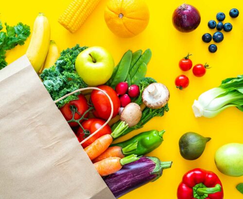 Fruit and vegetables spilling out of a paer shopping bag